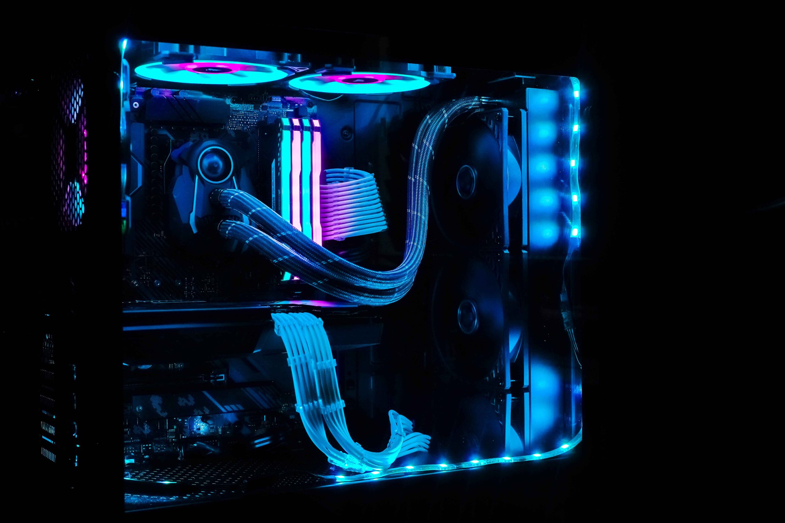 A high-performance custom gaming PC with RGB lighting, liquid cooling tubes, dual cooling fans, and illuminated RAM—showcasing a visually striking and powerful tech setup.