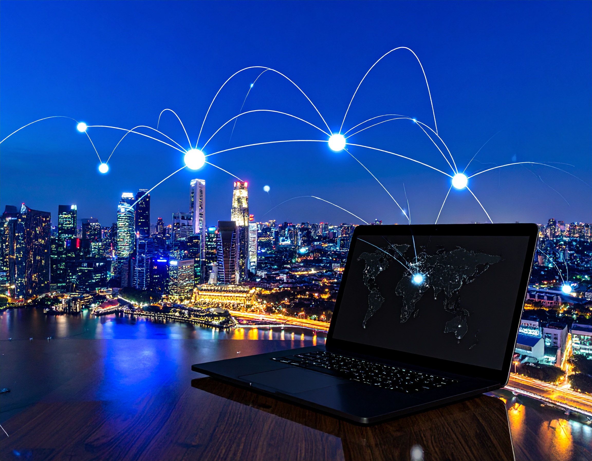 Laptop on a wooden table overlooking a city skyline at night, with glowing connection lines linking the computer to illuminated points in the sky, symbolizing global digital connectivity and networking.